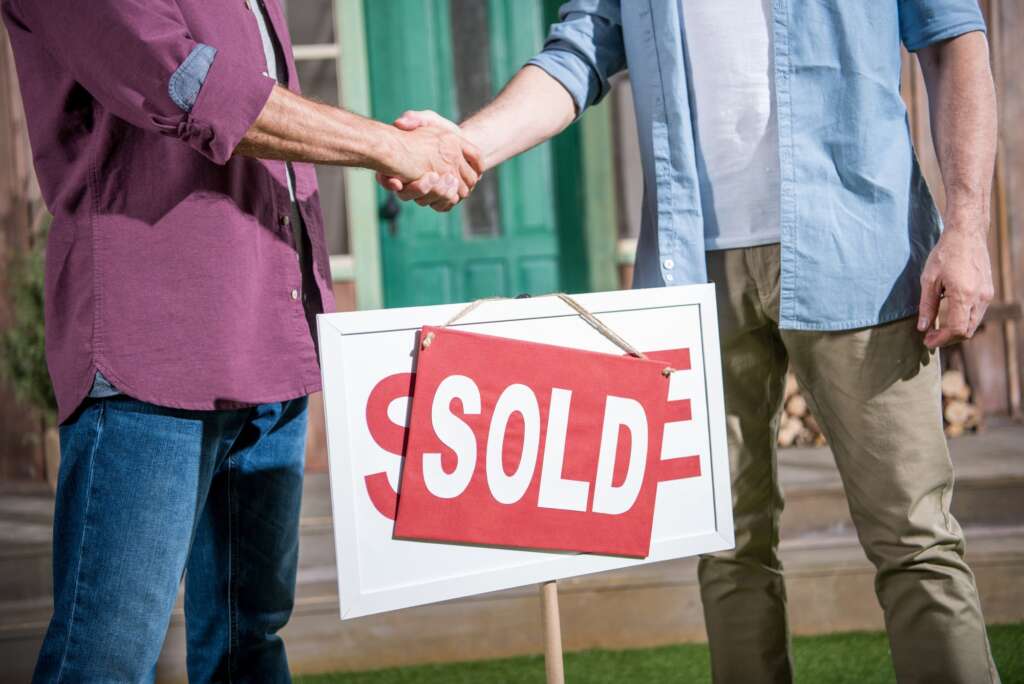 cropped view of men shaking hands with saleman and buying new house