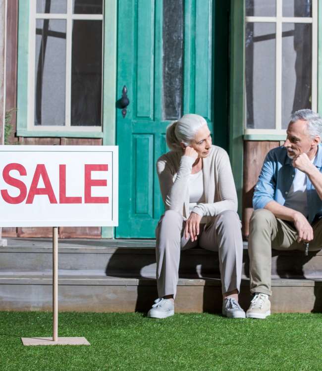 upset senior couple sitting on porch and selling their house, house for sale concept